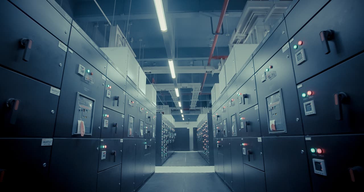 İki sıra elektrik panosu arasında uzanan aydınlatılmış pano dairesi koridoru