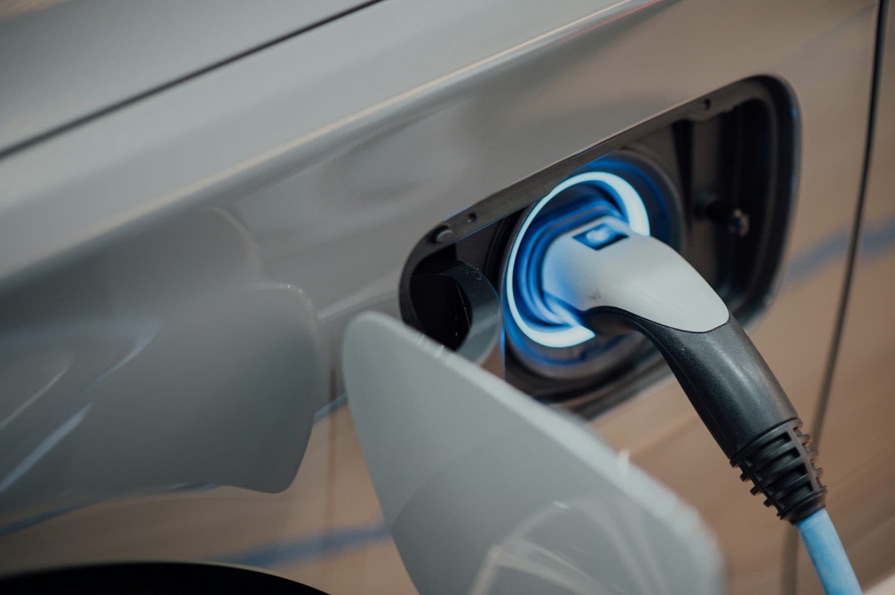 Elektrikli aracın şarj soketine takılı şarj fişi, yakın plan